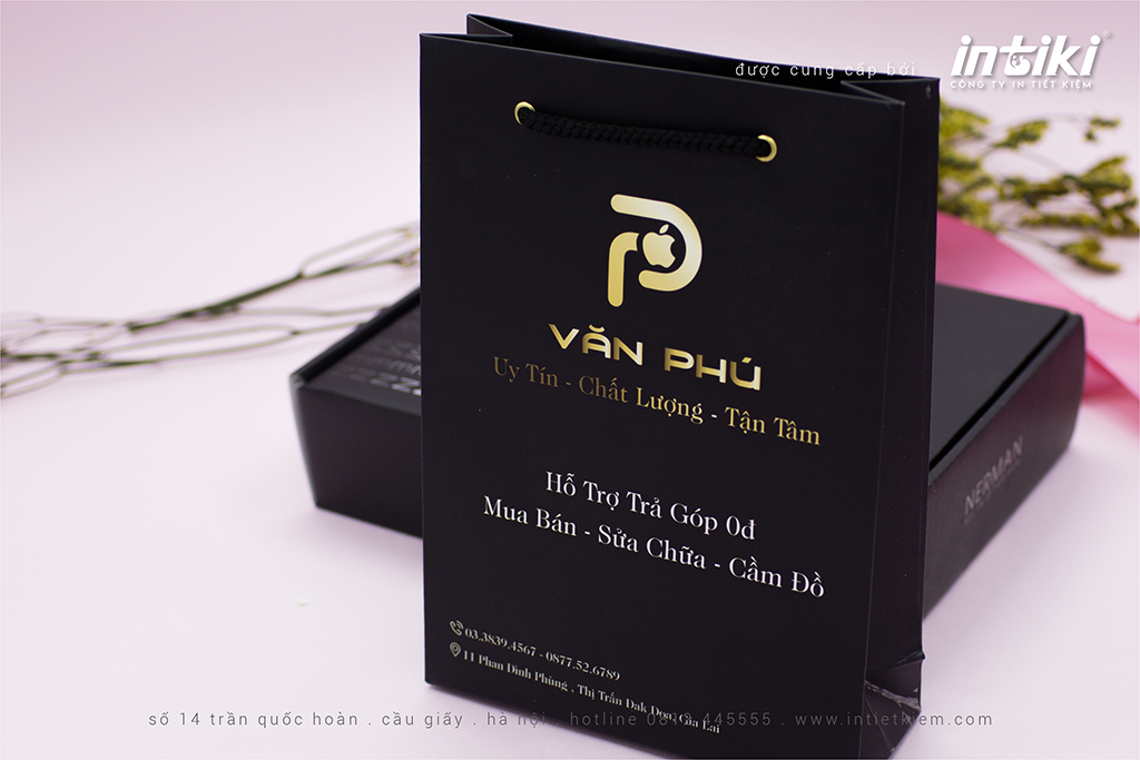 Khám phá mẫu túi giấy độc đáo của Văn Phú Mobile - shop điện thoại nổi tiếng với thiết kế logo vàng trên nền đen. Túi được làm từ giấy ivory 250gsm cán mờ cao cấp, kích thước lớn 15x5.5x21cm, phù hợp để đựng các sản phẩm điện thoại cao cấp.